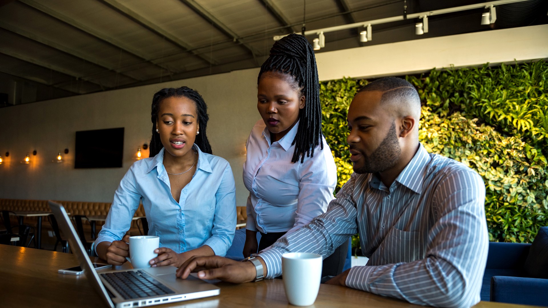 Colleagues collaborating around a laptop in a modern workspace